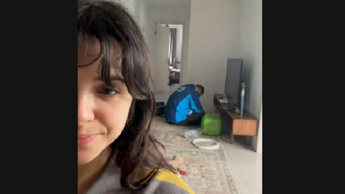 La joven, grabándose con el técnico dormido detrás.