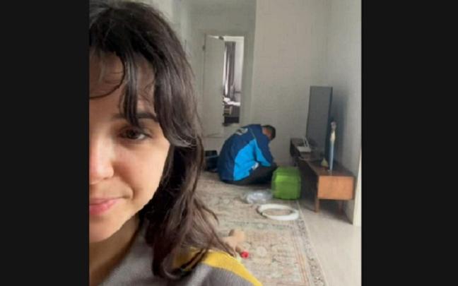 La joven, grabándose con el técnico dormido detrás.