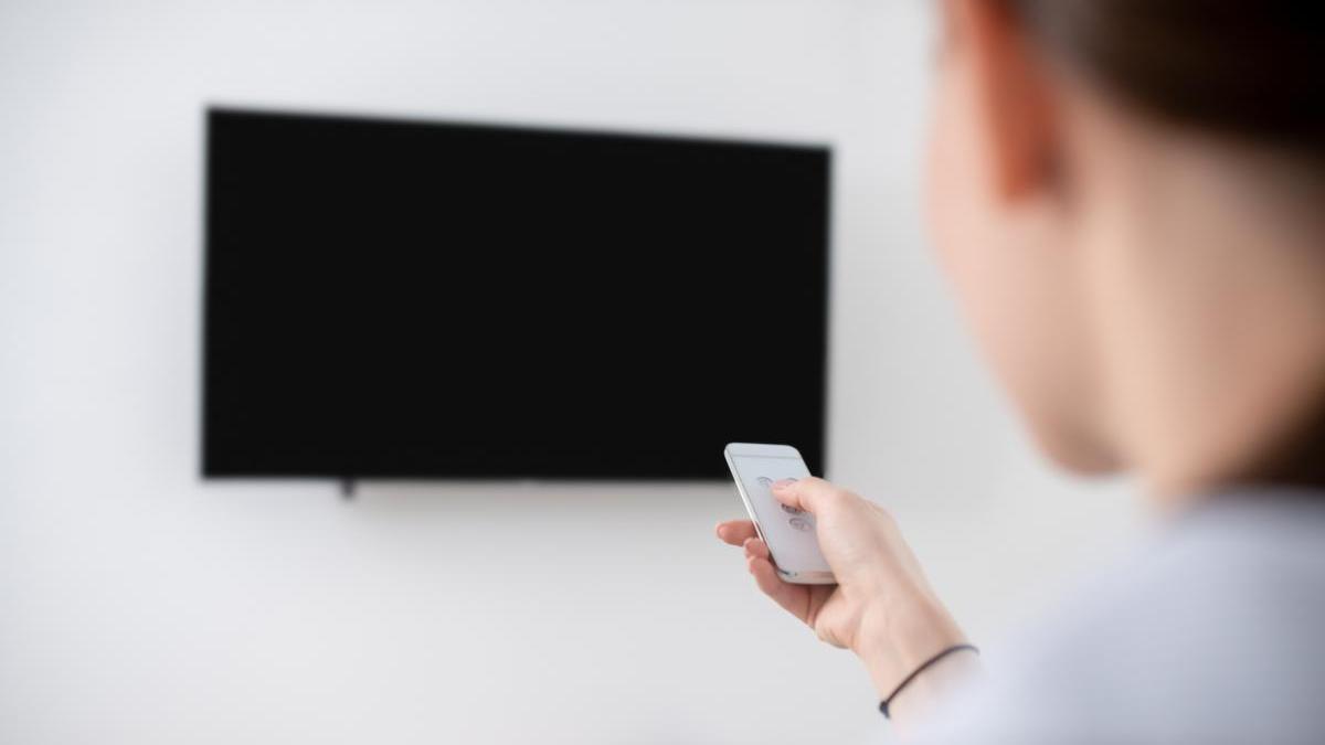 Mujer utiliza el mando a distancia para encender la televisión