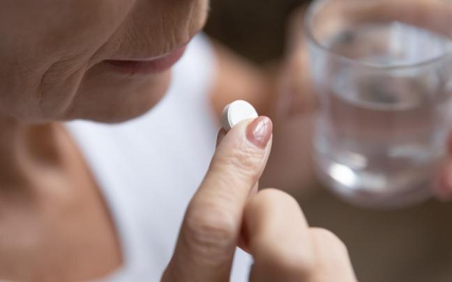 Una mujer toma una pastilla.