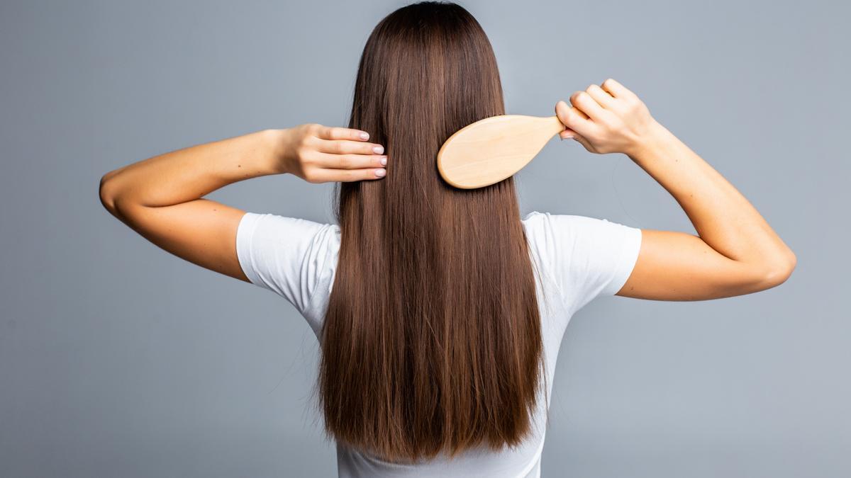 Mujer peinándose el pelo liso.