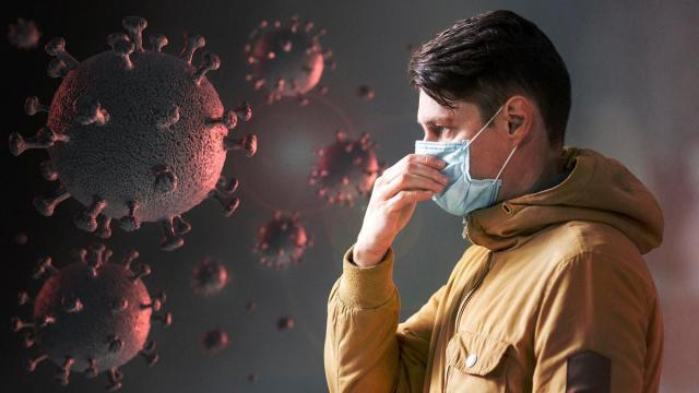 Un hombre con mascarilla junto a una representación de un virus.