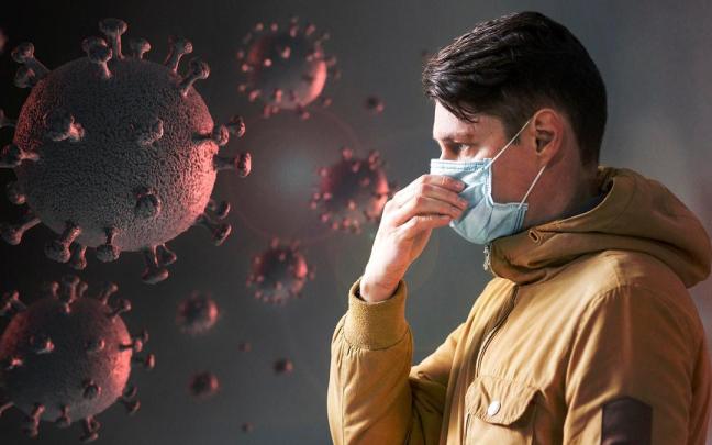 Un hombre con mascarilla junto a una representación de un virus.