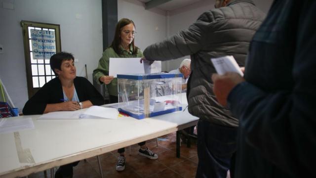 Varias personas ejercen su derecho a voto en la mesa electoral.