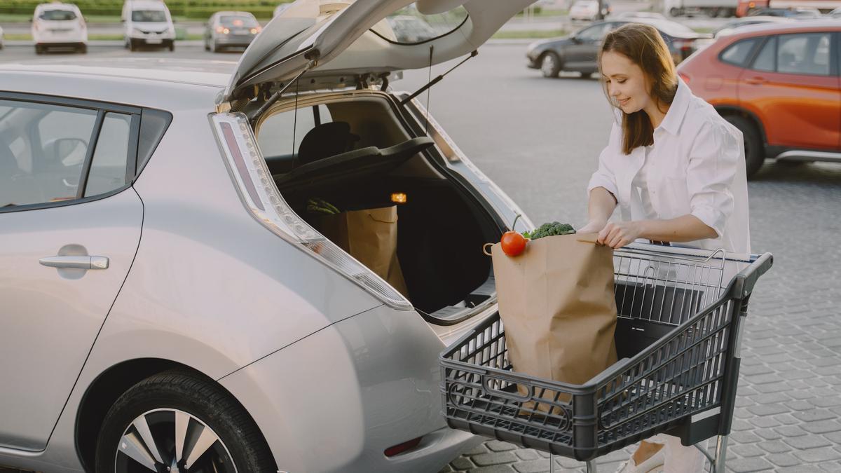 Una mujer guarda su compra en el maletero de su coche.