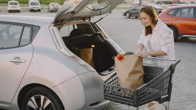 Una mujer guarda su compra en el maletero de su coche.