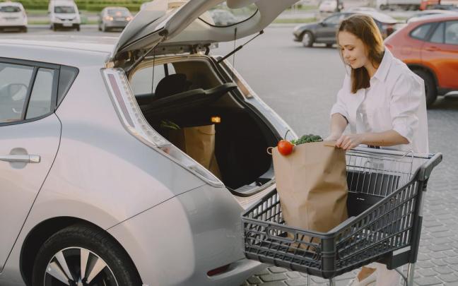 Una mujer guarda su compra en el maletero de su coche.