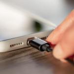 Una persona conecta un cargador a un teléfono móvil