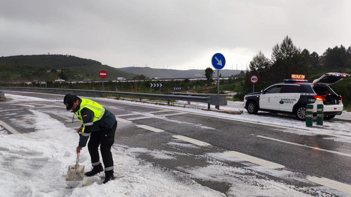 Un agente de la Guardia Civil retira granizo de la calzada con una pala. Redacción DNN