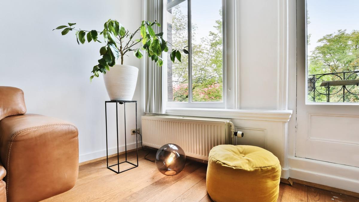 Un radiador colocado debajo de un ventanal en un salón.