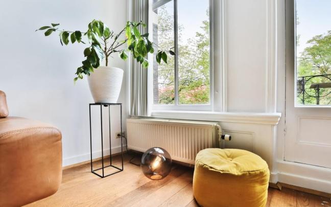 Un radiador colocado debajo de un ventanal en un salón.