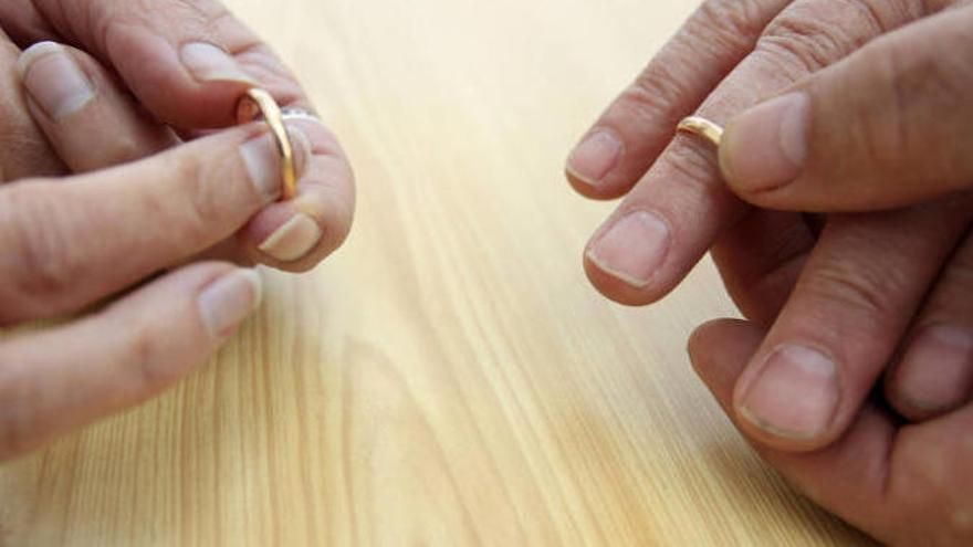 Manos de un matrimonio quitándose las alianzas para simbolizar su divorcio.