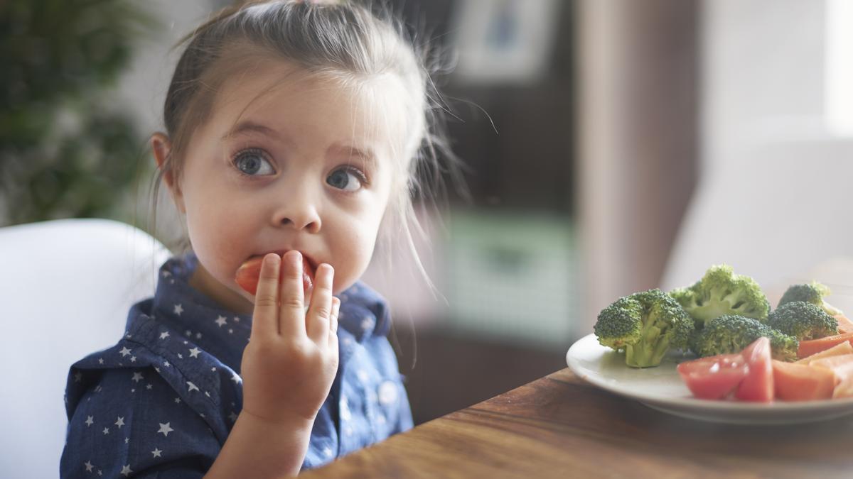 Niña comiendo verduras.