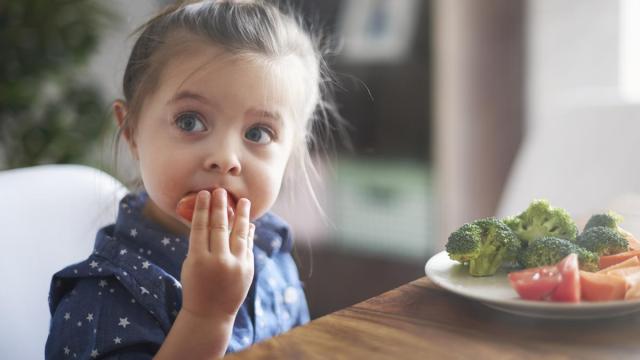 Niña comiendo verduras.