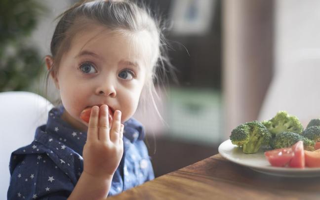 Niña comiendo verduras.