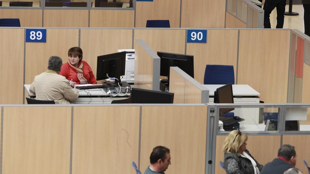 Una funcionaria atiende a un usuario en unas oficinas.