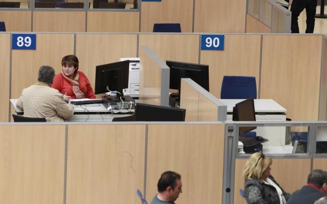 Una funcionaria atiende a un usuario en unas oficinas.