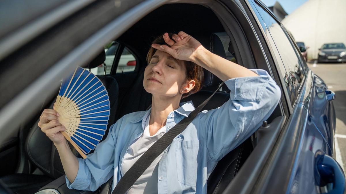 Una mujer con calor en el interior de su coche.