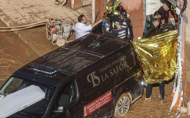 Un furgón de la funeraria sale de un garaje con cadáveres localizados tras el paso de la DANA