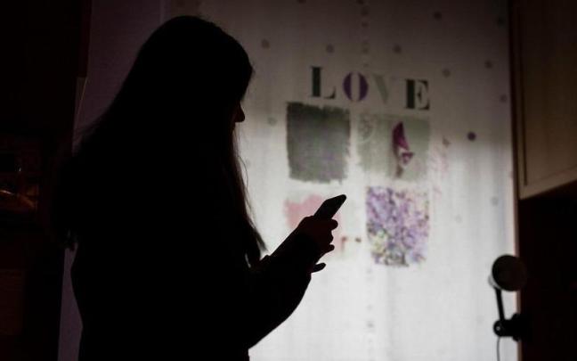 Una joven consulta su teléfono móvil.