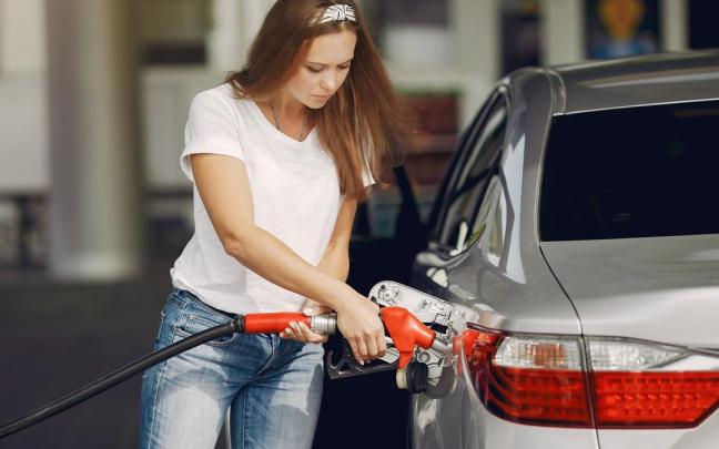 Una mujer reposta combustible en una gasolinera. Una mujer reposta combustible en una gasolinera.