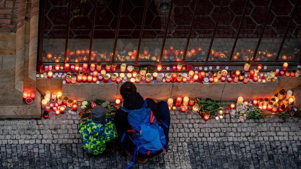 Dos personas encienden velas en el altar en homenaje a las víctimas de Praga.