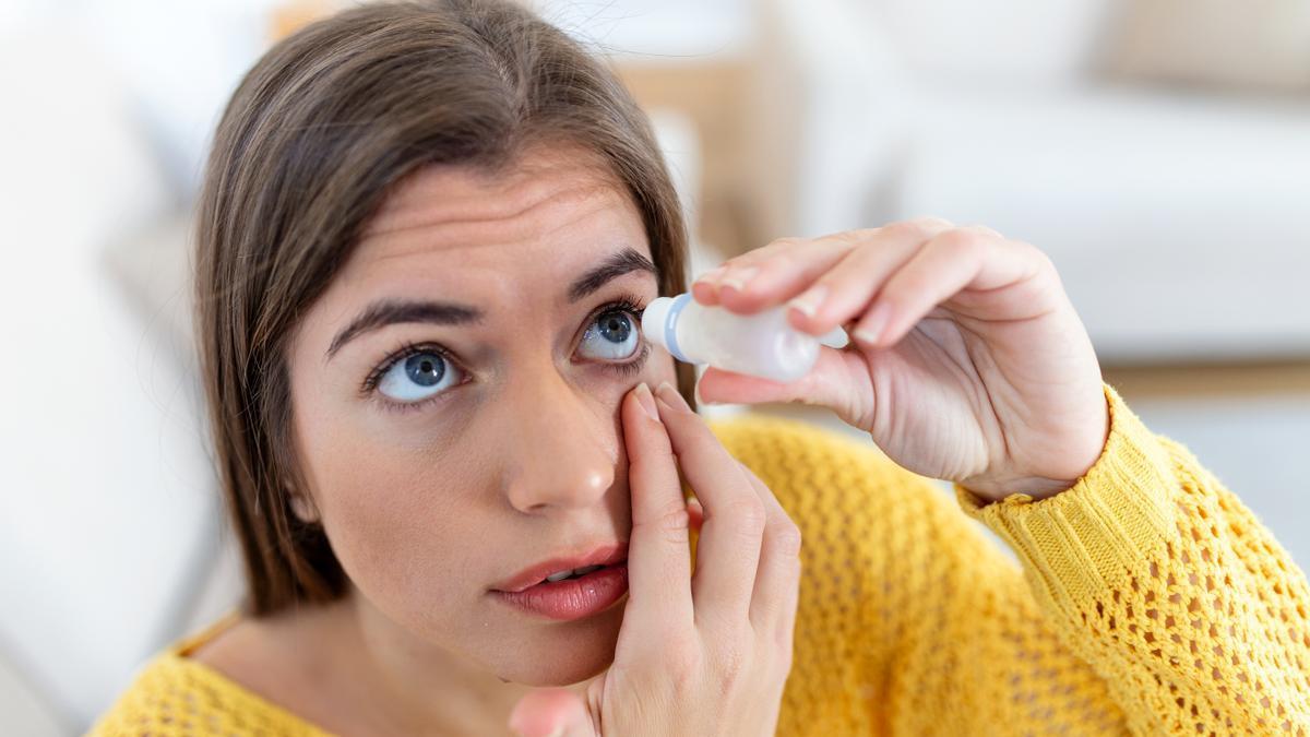 Una mujer usando lubricante ocular para tratar el ojo seco o alergia.