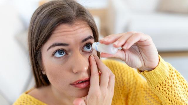 Una mujer usando lubricante ocular para tratar el ojo seco o alergia.