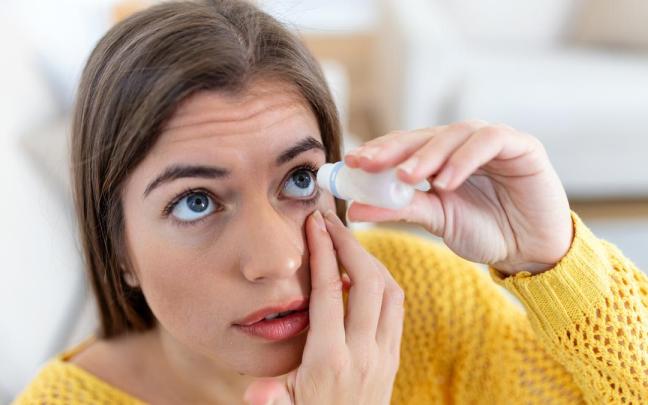 Una mujer usando lubricante ocular para tratar el ojo seco o alergia.