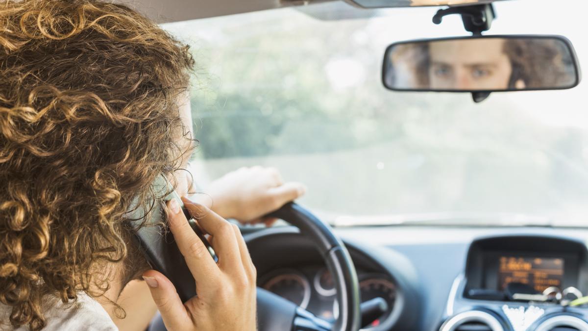 Conductor joven utilizando el teléfono móvil en el coche.