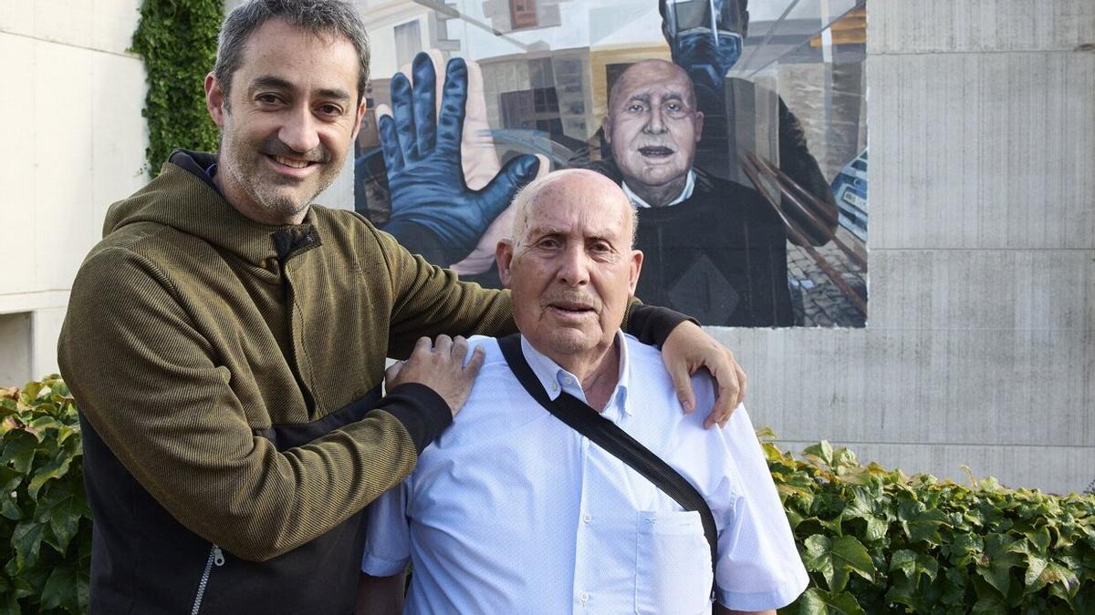 Unai Beroiz y Miguel Nieto, fotógrafo y retratado, nieto y abuelo, posan frente al mural realizado por Jabi Landa en la fachada del polideportivo Ugarrandia.