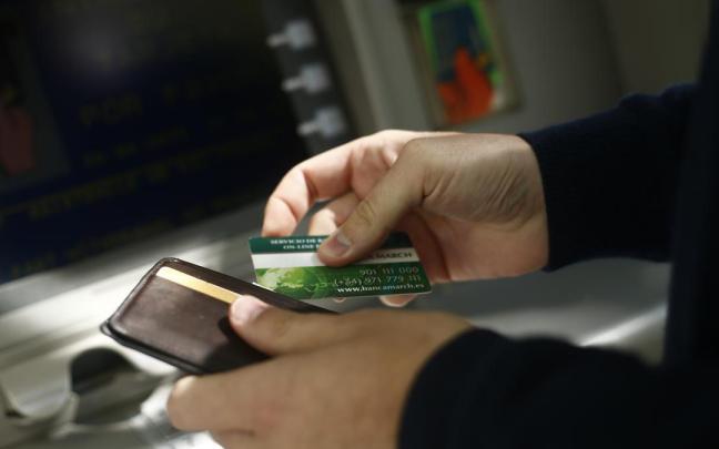 Un hombre saca dinero en un cajero. Un hombre saca dinero en un cajero.