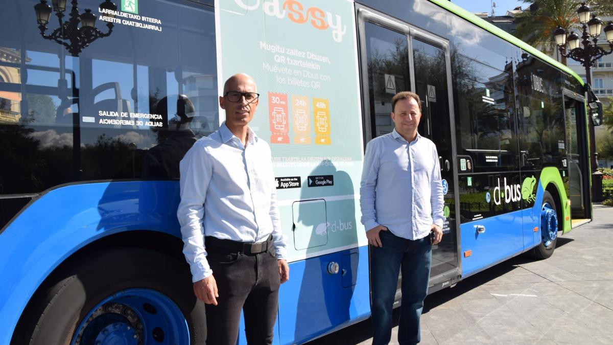 El director gerente de Dbus, Igor González, y el director adjunto, Javi Vallejo, junto a un vehículo con publicidad de la nueva opción.