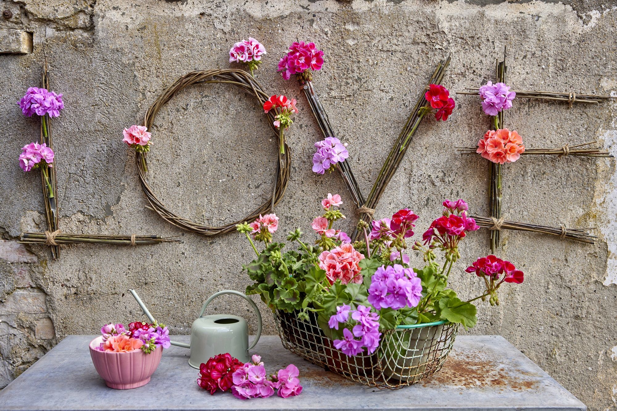 La palabra Love decorada con geranios sobre una pared.
