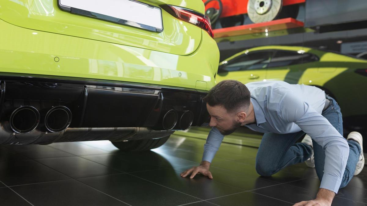 Un hombre inspeccionando su coche.