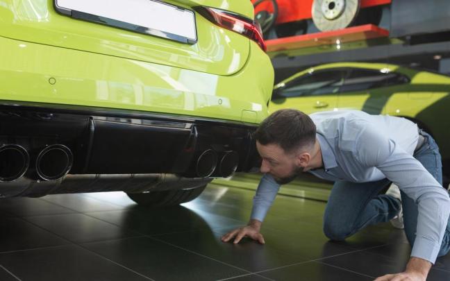 Un hombre inspeccionando su coche.