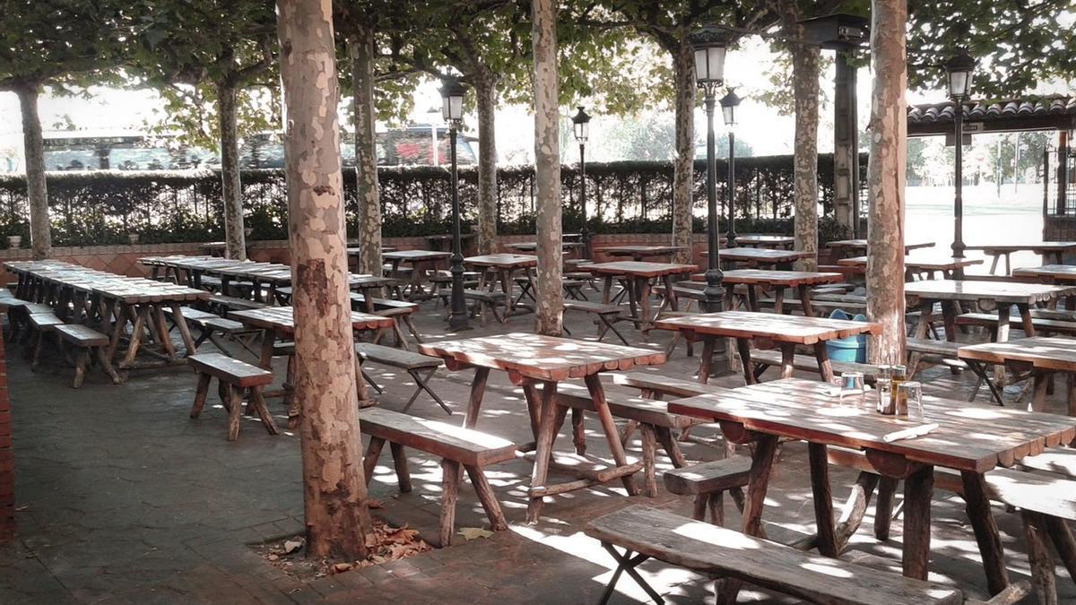 Terraza de La Duna en verano, con mesas y bancos de madera para grupos grandes y pequeños