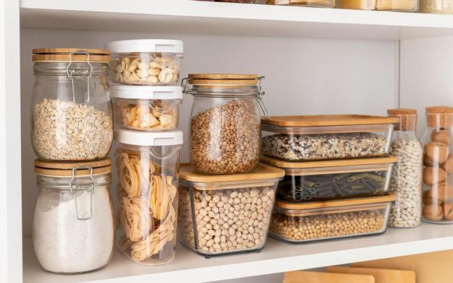 Pasta, legumbres y otros alimentos en una estantería.