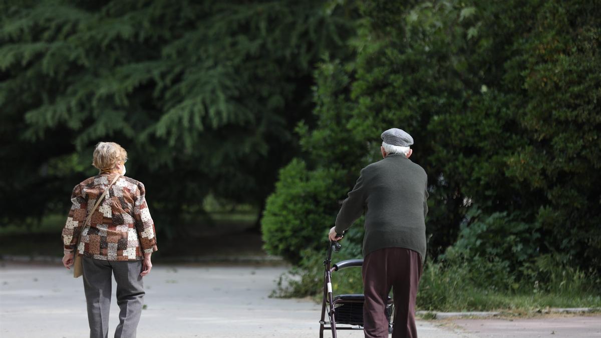 Una persona mayor se ayuda de un andador para poder pasear por la calle.
