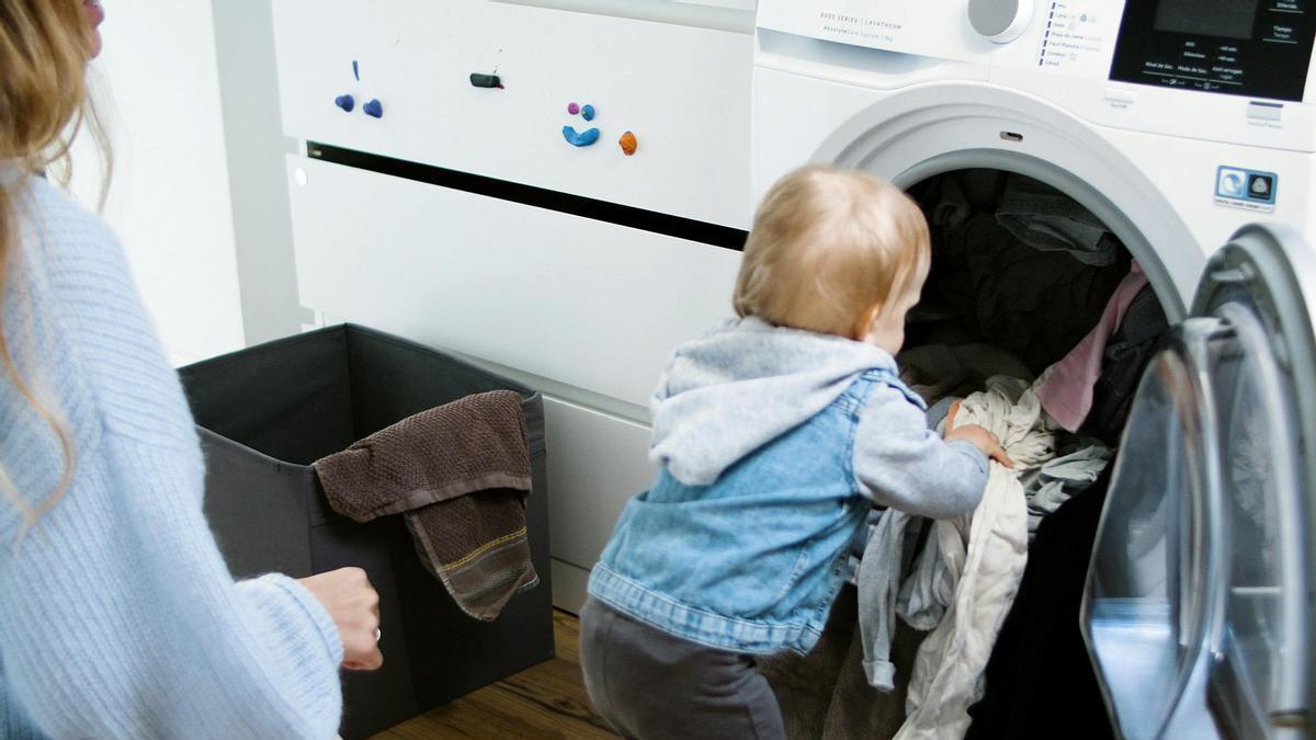 Niño aprende las tareas del hogar bajo la supervisión de su madre