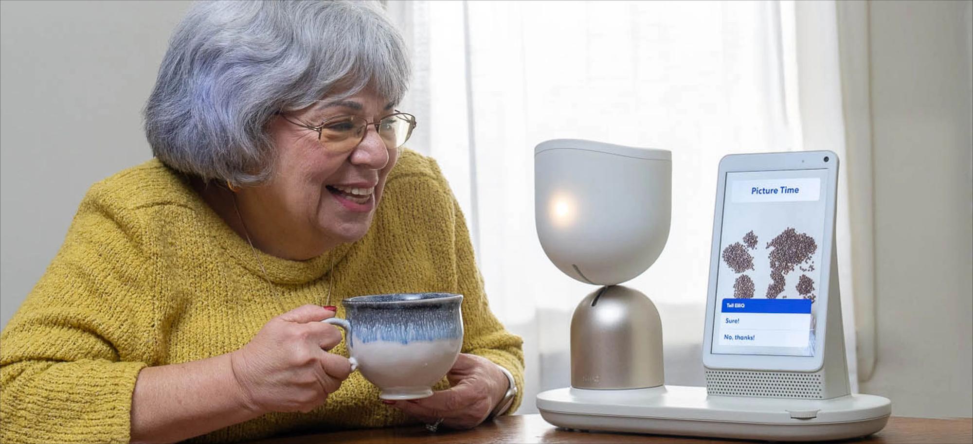 Una anciana habla con el dispositivo mientras toma un café.