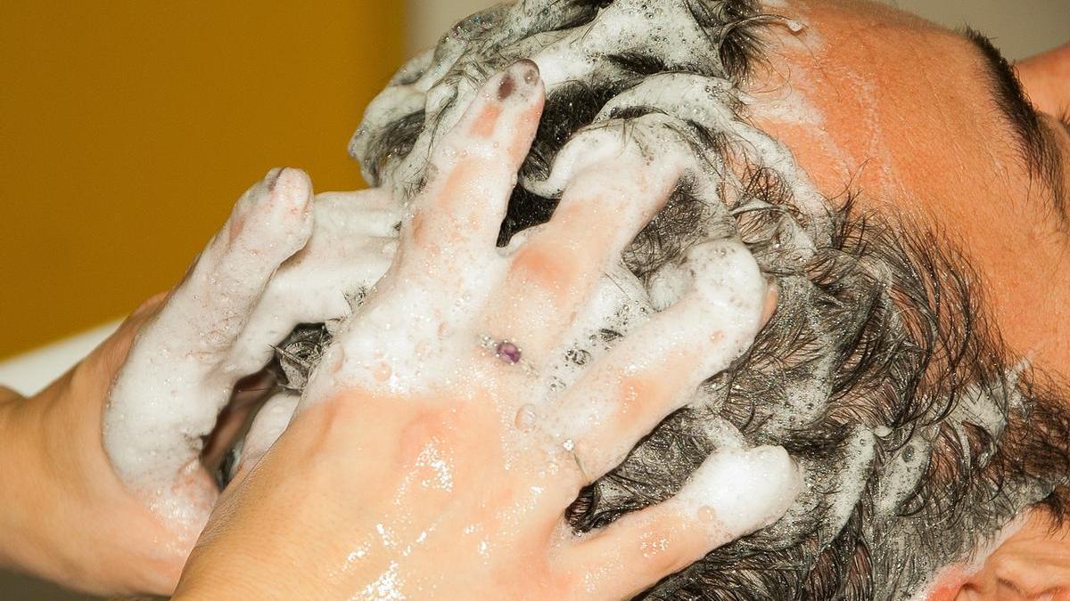 Hombre lavándose el pelo en la peluquería con un champú adecuado a sus necesidades capilares