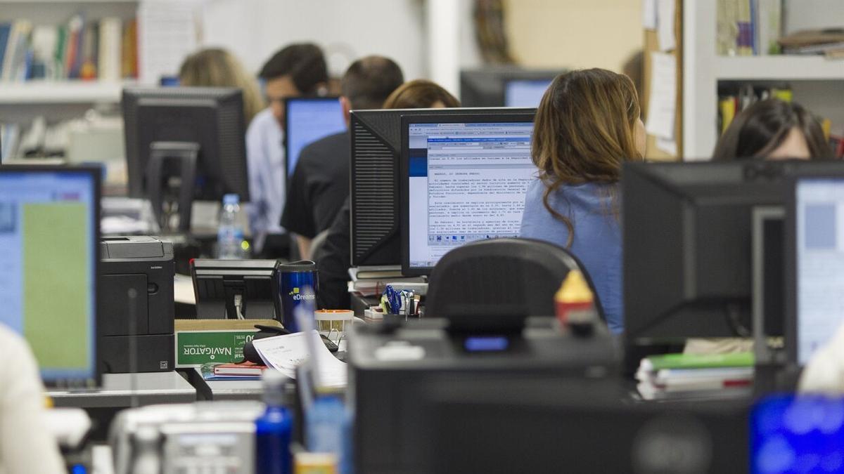 Trabajadores sentados frente a sus ordenadores en una oficina.