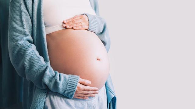 Una mujer embarazada en avanzado estado de gestación se toca la barriga.