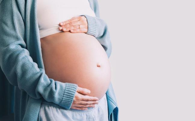 Una mujer embarazada en avanzado estado de gestación se toca la barriga.