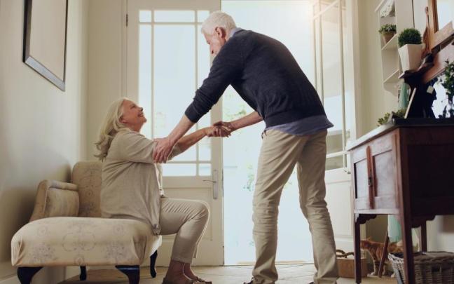 Pareja de personas mayores se prepara antes de salir de casa.
