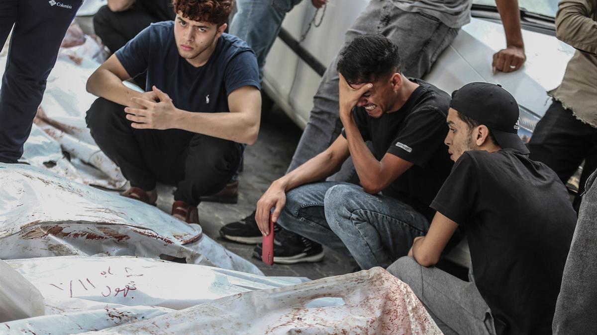 Jóvenes palestinos frente a los cadáveres de varias personas fallecidas por los bombardeos israelíes en Gaza.