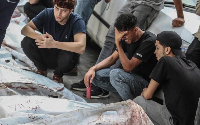 Jóvenes palestinos frente a los cadáveres de varias personas fallecidas por los bombardeos israelíes en Gaza.