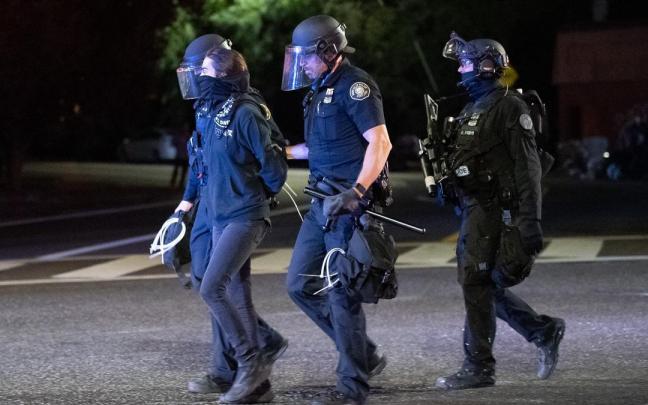 Policías se llevan arrestada a una manifestante en Portland.