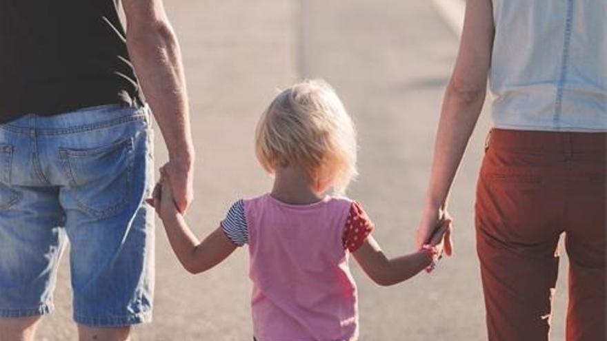Una niña coge a sus padres de la mano.